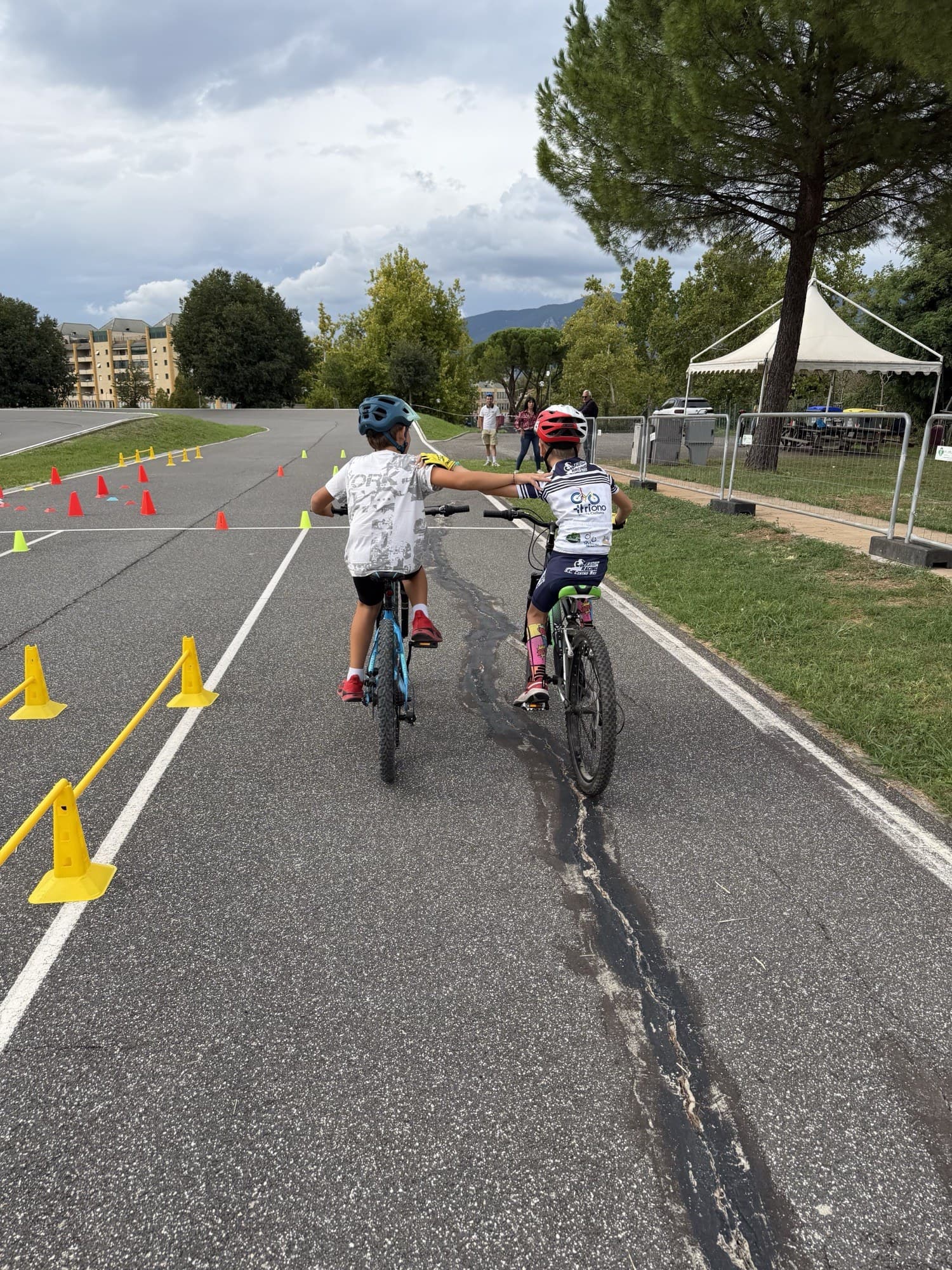 Due piccoli allievi Triono pedalano insieme tra i birilli della pista del ciclodromo