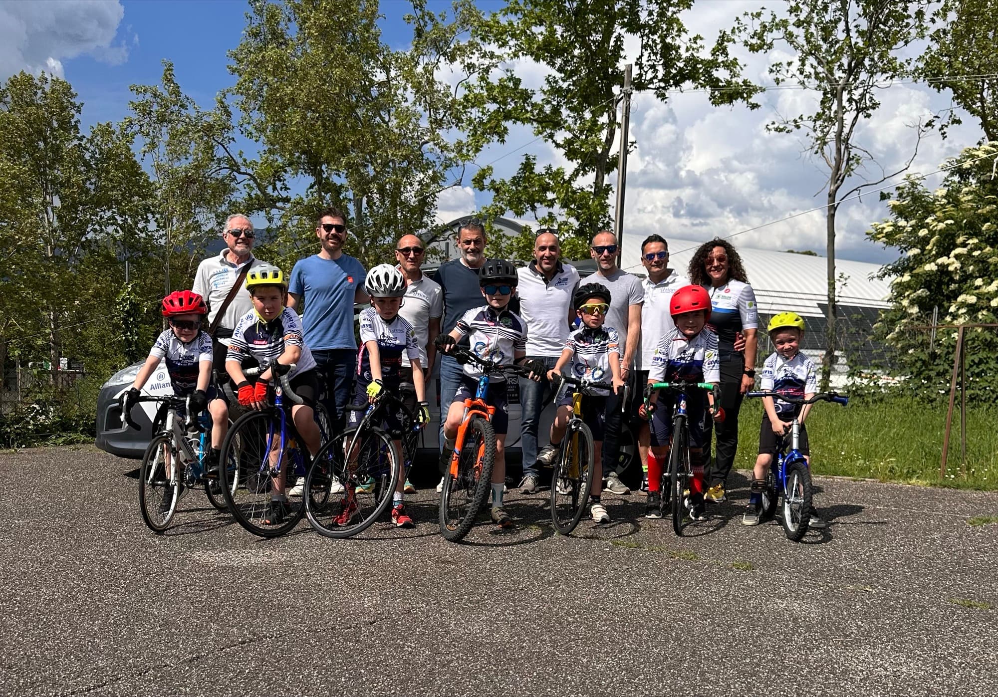 Foto di gruppo di allievi della Scuola Triono in sella alle bici insieme ai maestri, giornata di sole