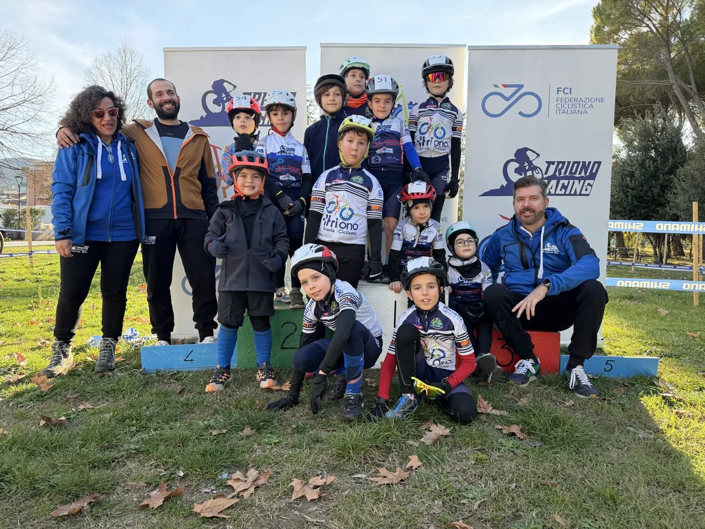 La squadra della Scuola Triono al completo con i maestri davanti al podio, accanto agli striscioni della Federazione Ciclistica Italiana